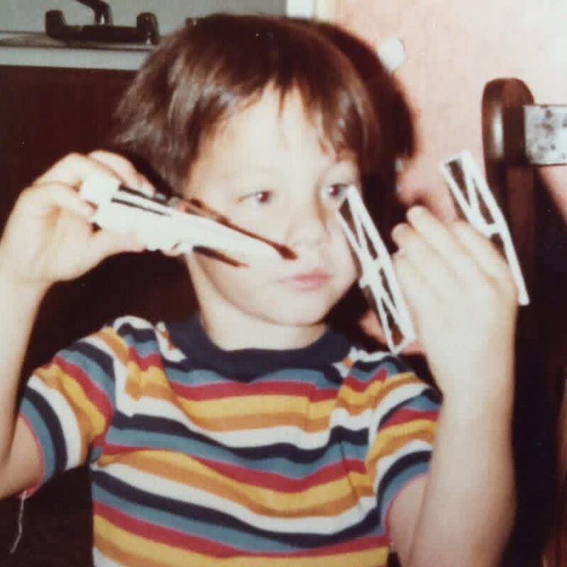 Justin Lewis as a young child in a striped shirt, fighting a space battle